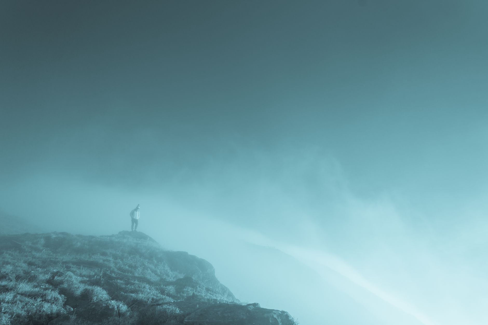 methylene blue for brain fog — A lone person stands on a misty mountain cliff under a dramatic sky.