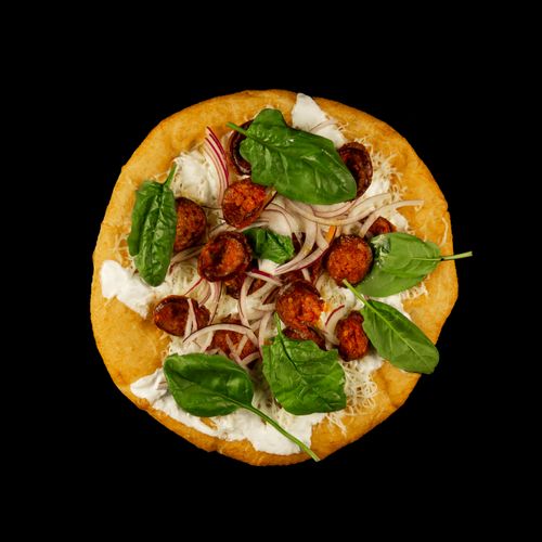 Free Close-up of a delicious pizza with sausage, cheese, and fresh spinach on a black background. Stock Photo