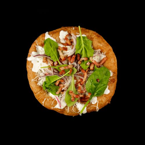 Free Delicious Slovak lángos with fresh toppings on a black background, showcasing traditional street food presentation. Stock Photo