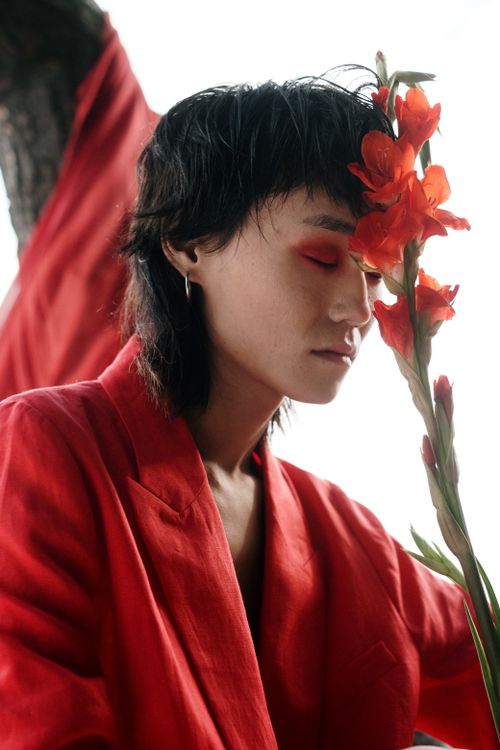 Free Stylish portrait of a man in red suit with closed eyes and flowers, exuding conceptual elegance. Stock Photo