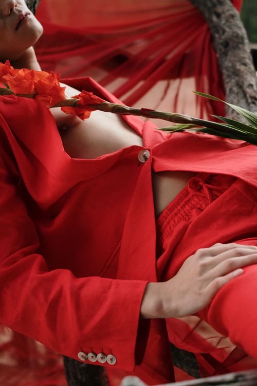 Free Artistic photograph of a person in a red suit with flowers, blending fashion and nature. Stock Photo