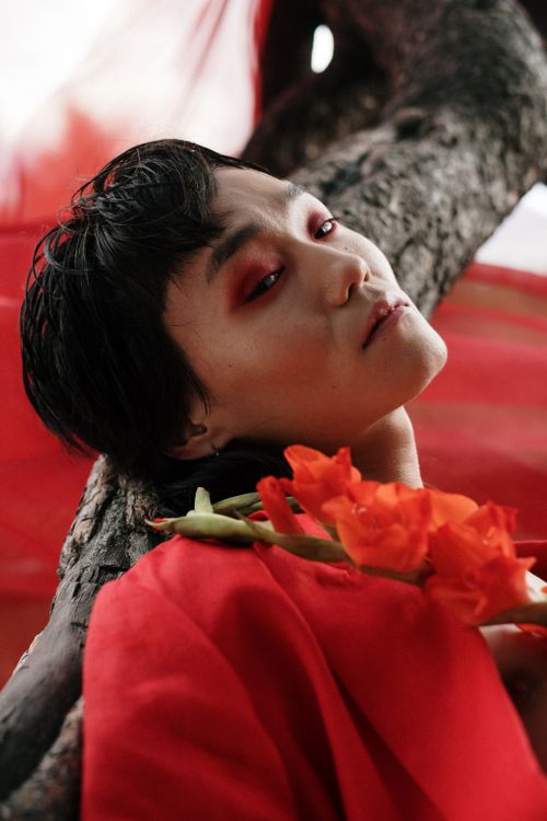 Free A conceptual portrait of an adult in a red outfit with flowers, exuding vibrant artistic expression. Stock Photo