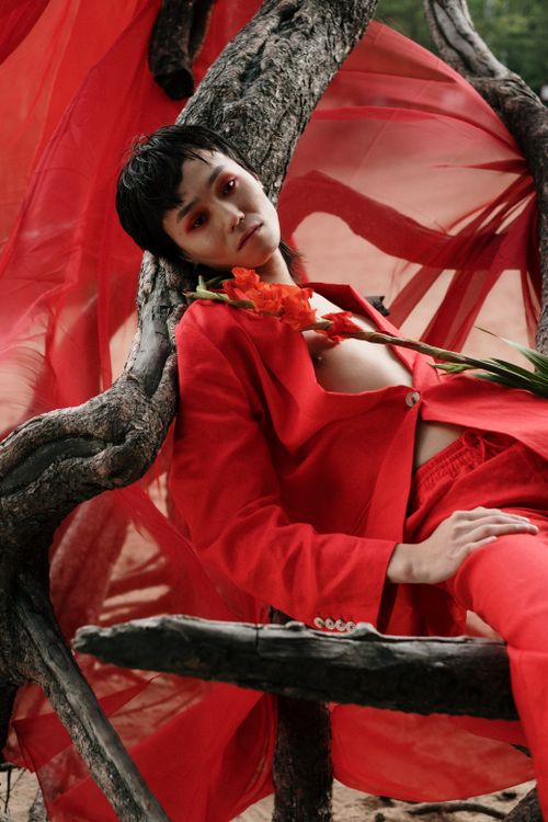 Free Stylish portrait of a model in vibrant red with striking makeup and a dynamic background. Stock Photo