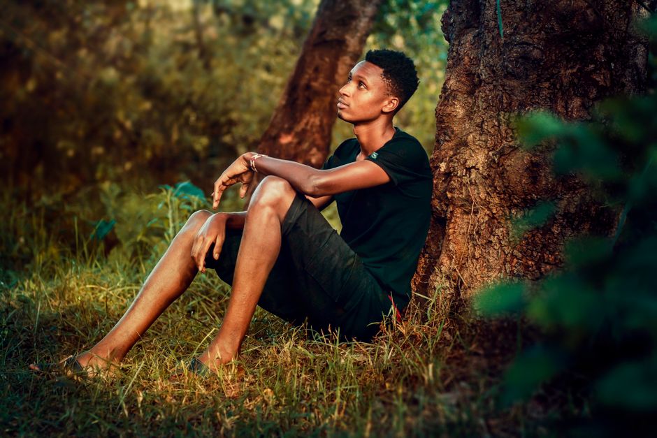 A young man resting in the shade of a tree during the hottest part of the day, Kiambu County, Kenya.