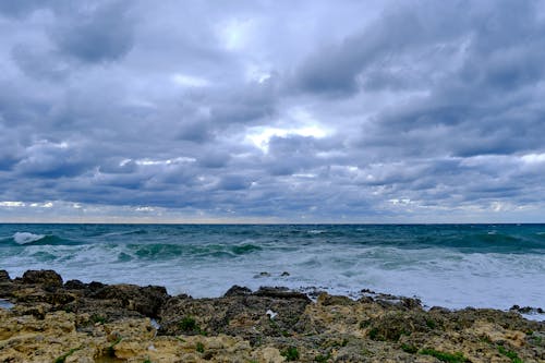 Crashing Ocean Waves on the Rocky Shore under the Cloudy Sky
