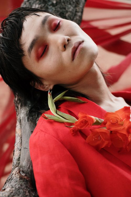 Free Artistic portrait of a person with red eye makeup and floral accents. Stock Photo