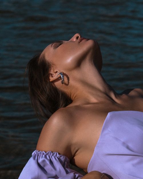 Free Stylish woman enjoying a peaceful moment by the water, showcasing fashion and tranquility. Stock Photo