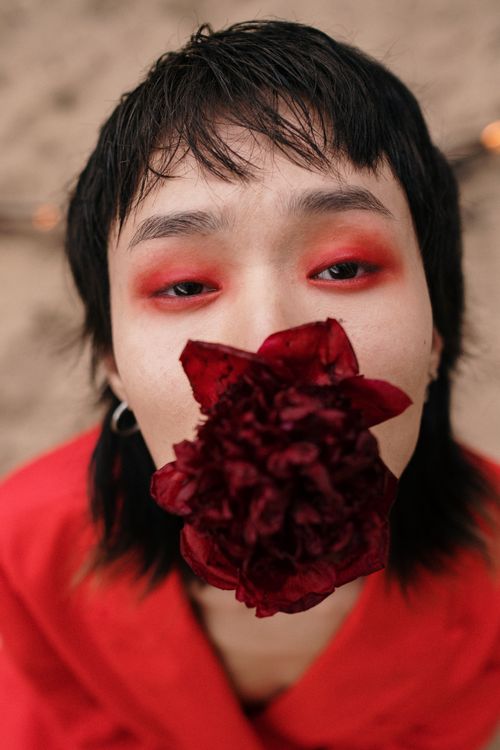 Free Captivating close-up of a person with vibrant red eyeshadow and flower. Stock Photo