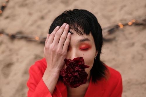 Free Conceptual portrait of a person with vibrant red makeup and flower outdoors. Stock Photo