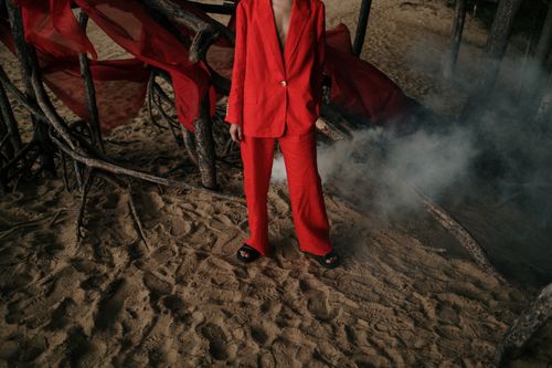 Free A person wearing a red suit stands on sandy forest terrain surrounded by smoke and twisted branches. Stock Photo