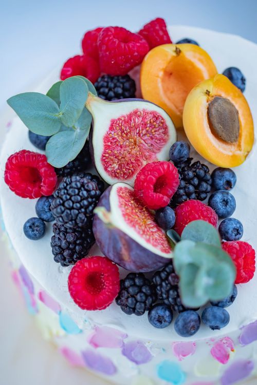 Free Delicious cake adorned with fresh vibrant fruits including figs, apricots, and berries. Stock Photo