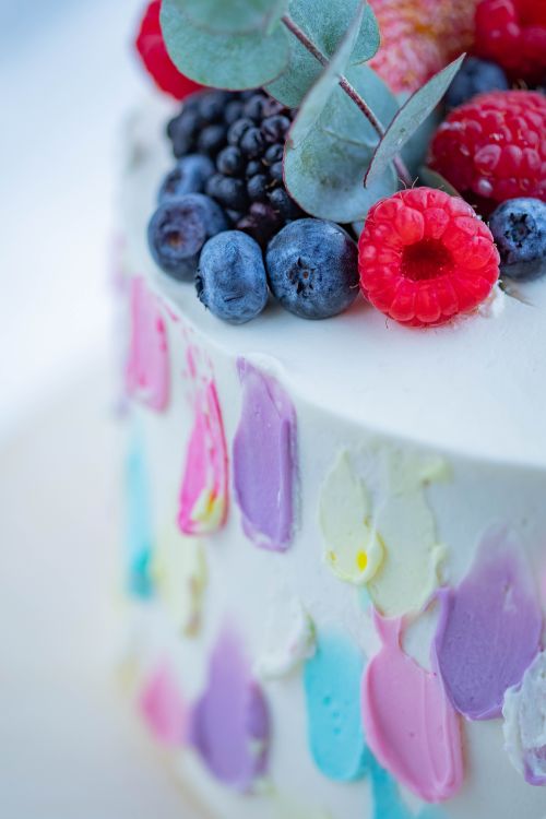 Free Vibrant cake topped with fresh berries and colorful icing close-up. Stock Photo