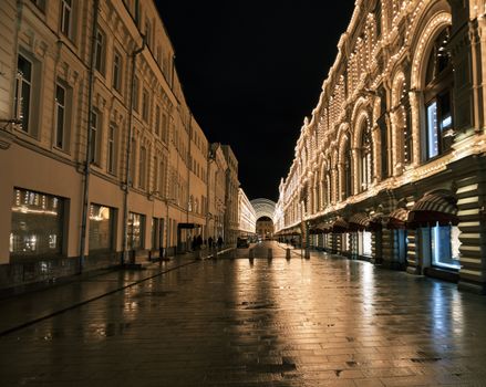 A beautifully illuminated street with historic buildings at night, creating a vibrant cityscape.