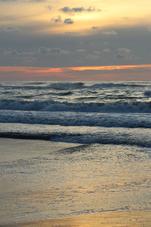 Free Capture the serene beauty of ocean waves during a golden sunset on the beach. Stock Photo