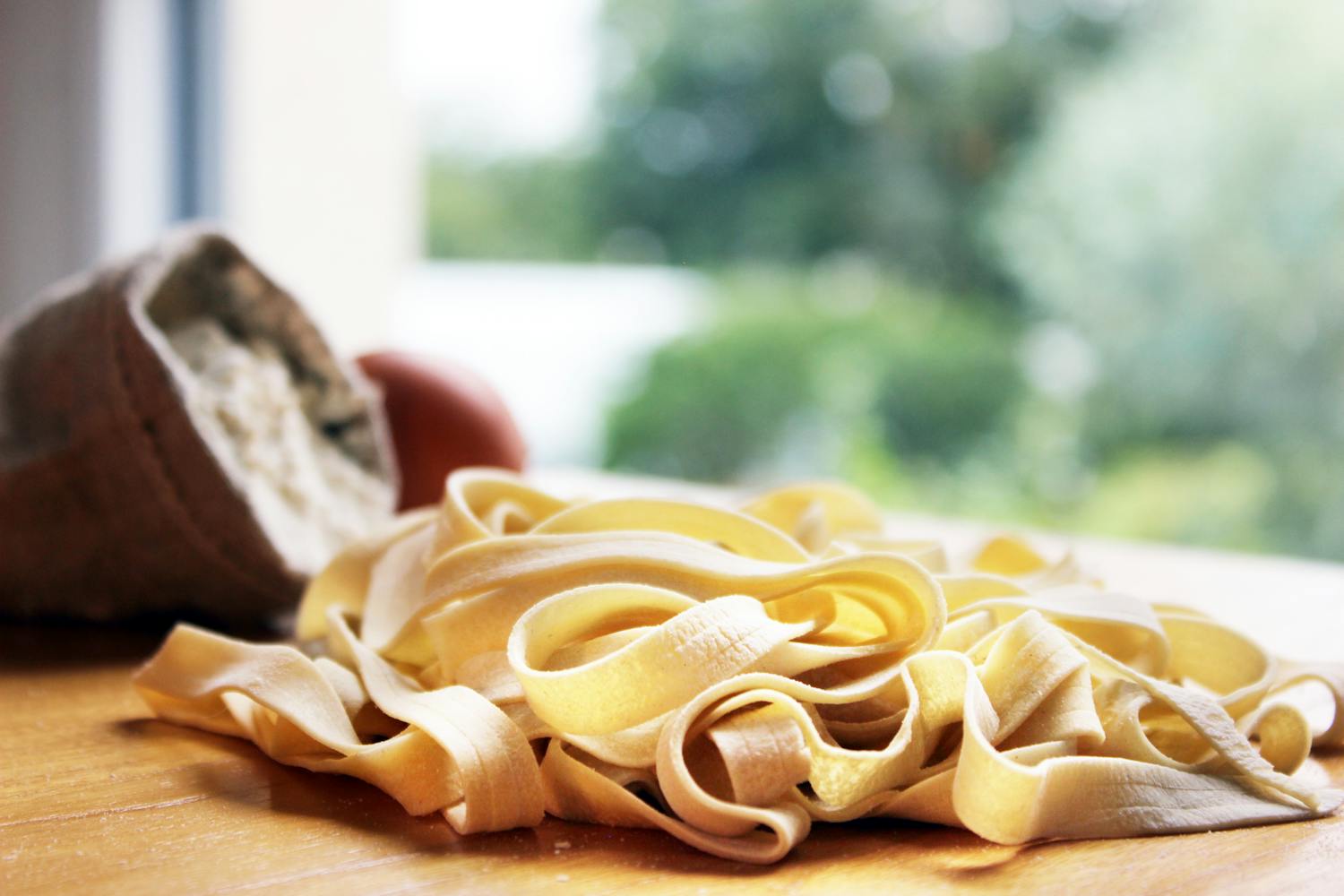 Fresh uncooked tagliatelle pasta with flour bag