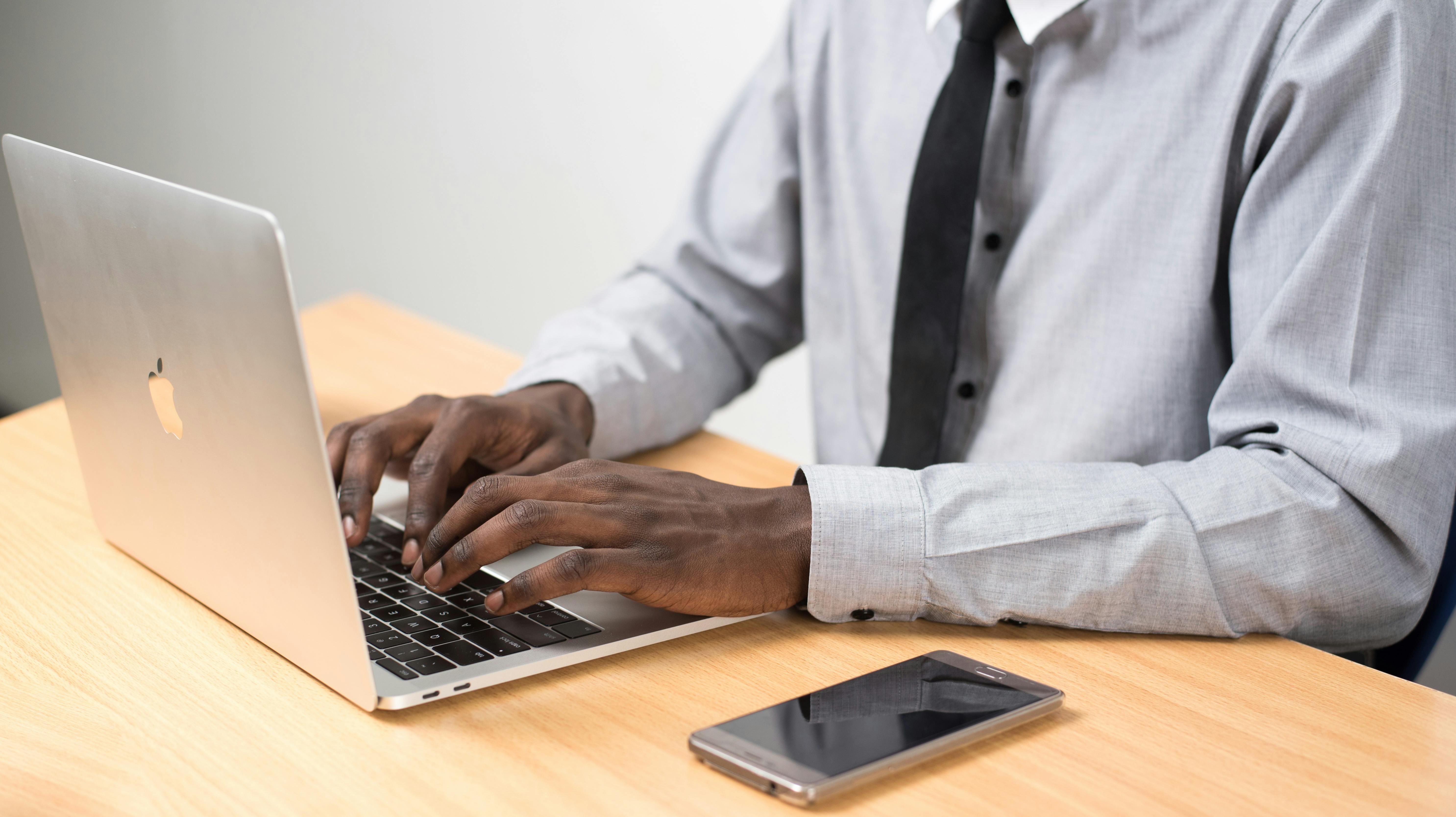 person sitting in front of table using laptop beside smartphone