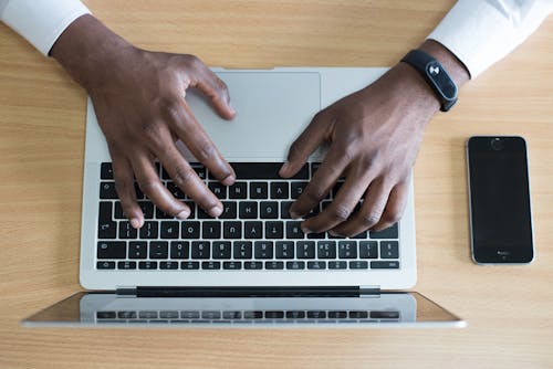 Closeup Photo of Person's Hands on Macbook Beside Space Gray Iphone 5s