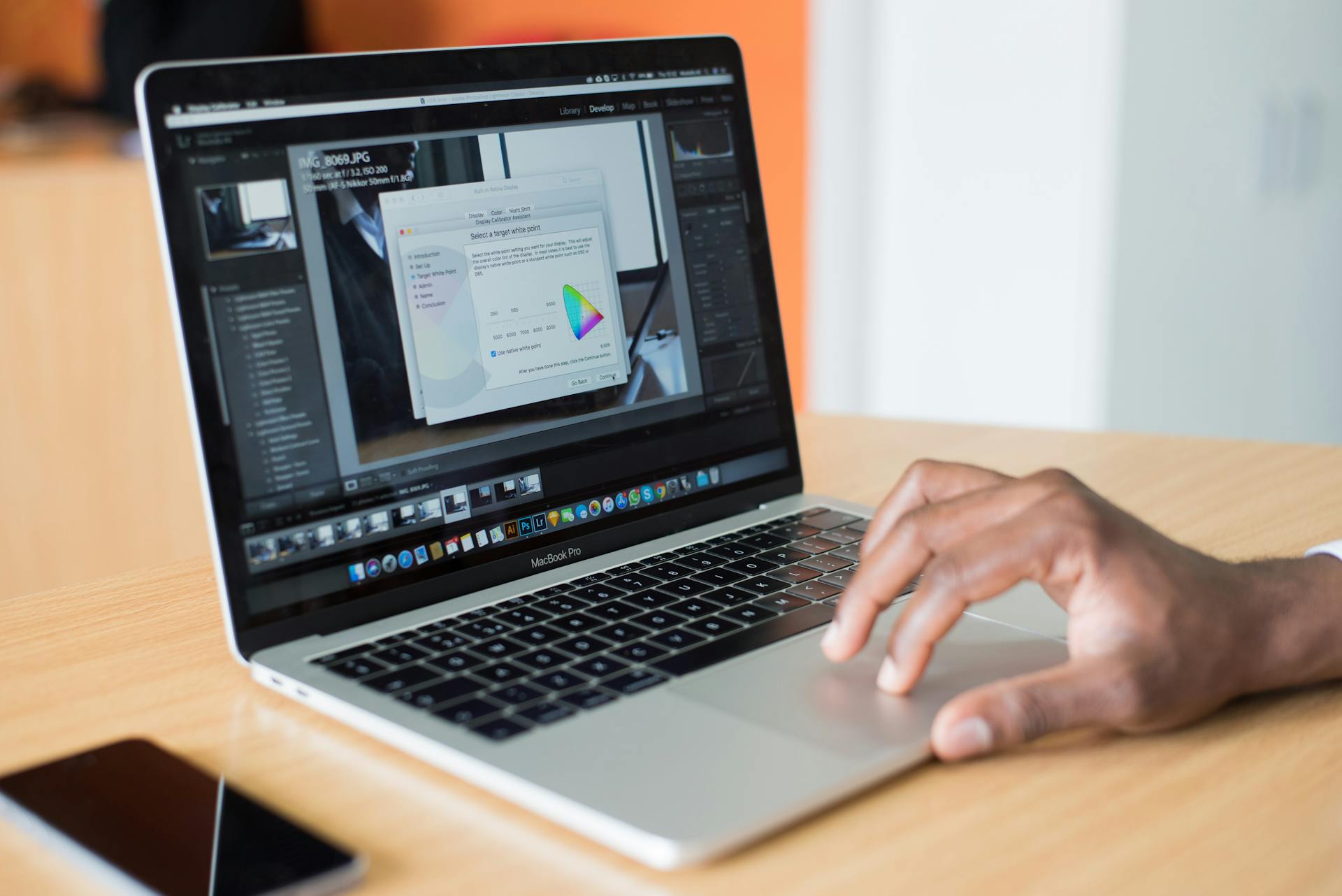 A person editing photos on a laptop in an office, showcasing technology use.