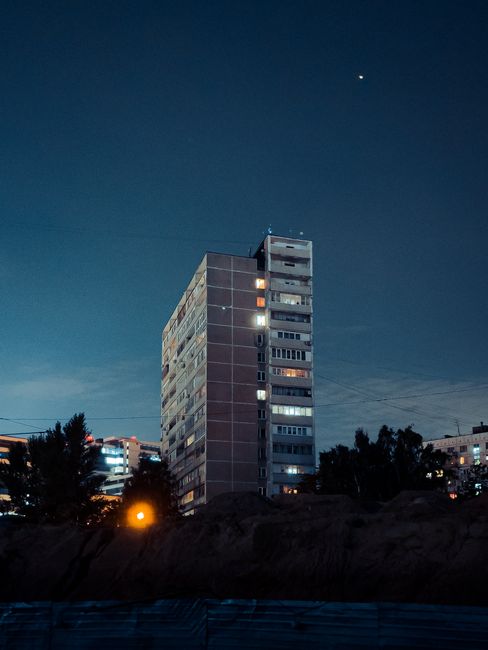 A high-rise building stands illuminated against the night sky in an urban landscape.
