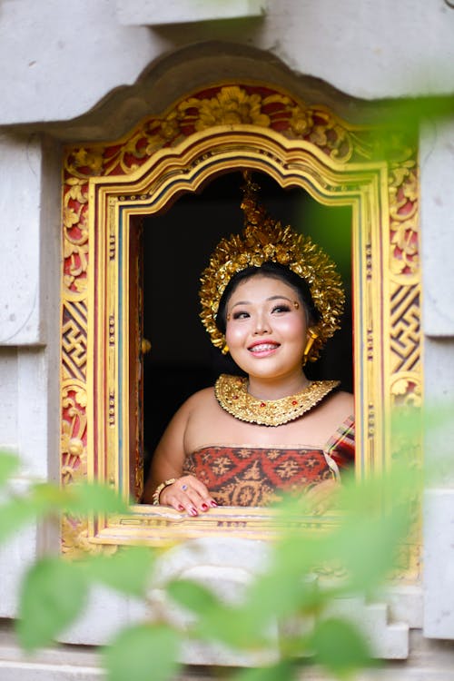 A Woman Wearing Golden Headdress Looking Out the Window