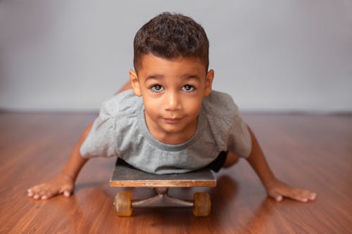 Free Boy in Gray Crew Neck T-shirt Sitting on Brown Wooden Chair Stock Photo
