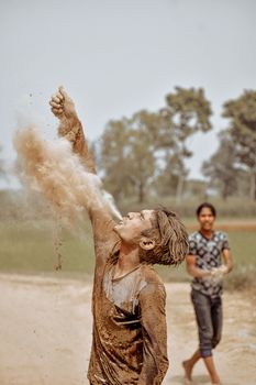 Two young men enjoying a playful moment outdoors with dust and mud.