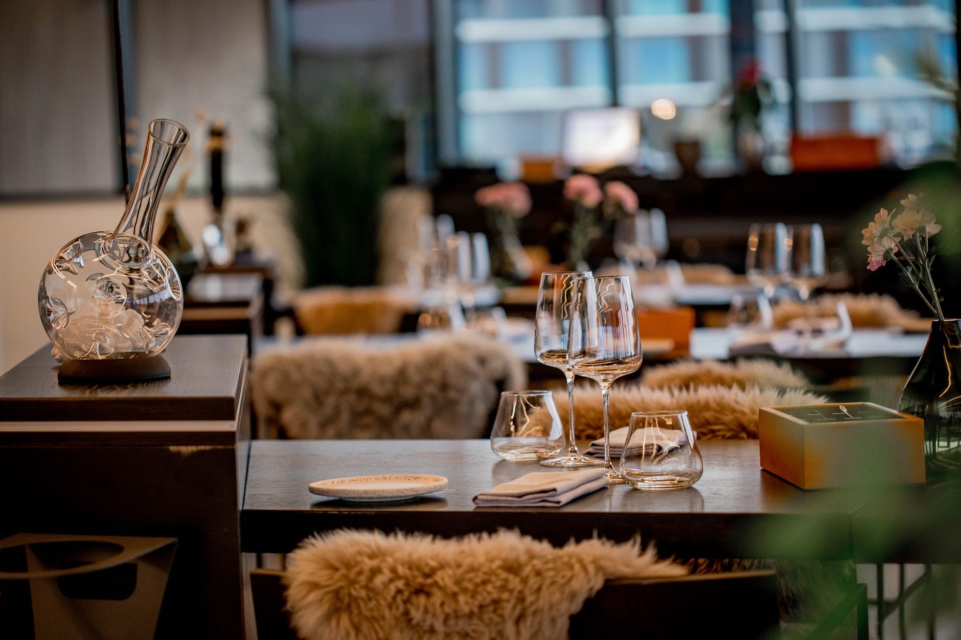 An elegantly set fine dining table in a minimalist luxury restaurant with soft warm lighting.