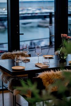 Sophisticated table setting with flowers and wine glasses by the waterfront, perfect for elegant dining.