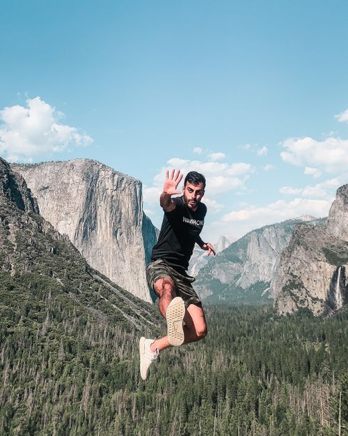 Free A man jumps energetically in Yosemite Valley with scenic views of natural rock formations. Stock Photo