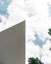 A Slanted Building Wall Under Blue Sky with White Clouds