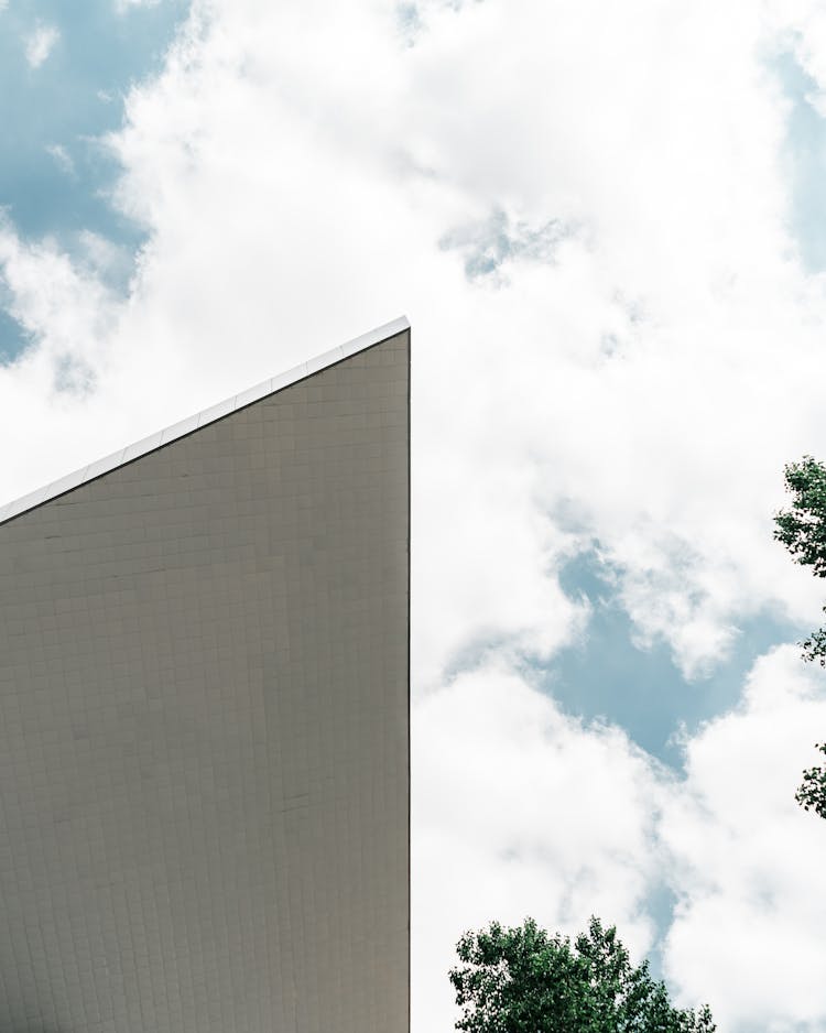 A Slanted Building Wall Under Blue Sky With White Clouds