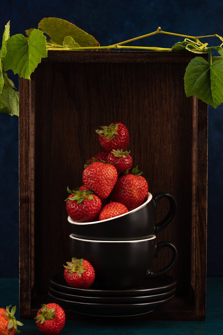 A Stack Of Cups, Plates And Strawberries In A Wooden Box