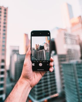 Hand holding smartphone capturing downtown cityscape in Houston.