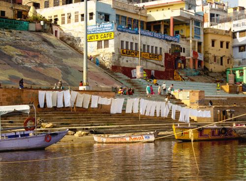 Free Boats and laundry by the riverside steps in Varanasi, India, showcasing daily life. Stock Photo
