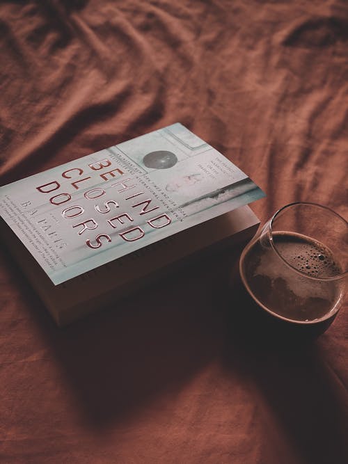 A Book Beside a Glass of Drink with Bubbles on Brown Fabric