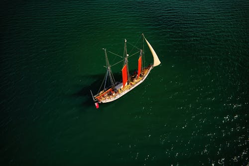 Free White and Brown Sail Boat on Green Body of Water Stock Photo