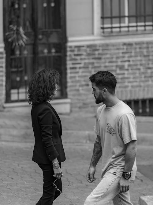 Man and Woman Walking on Sidewalk in Grayscale Photography
