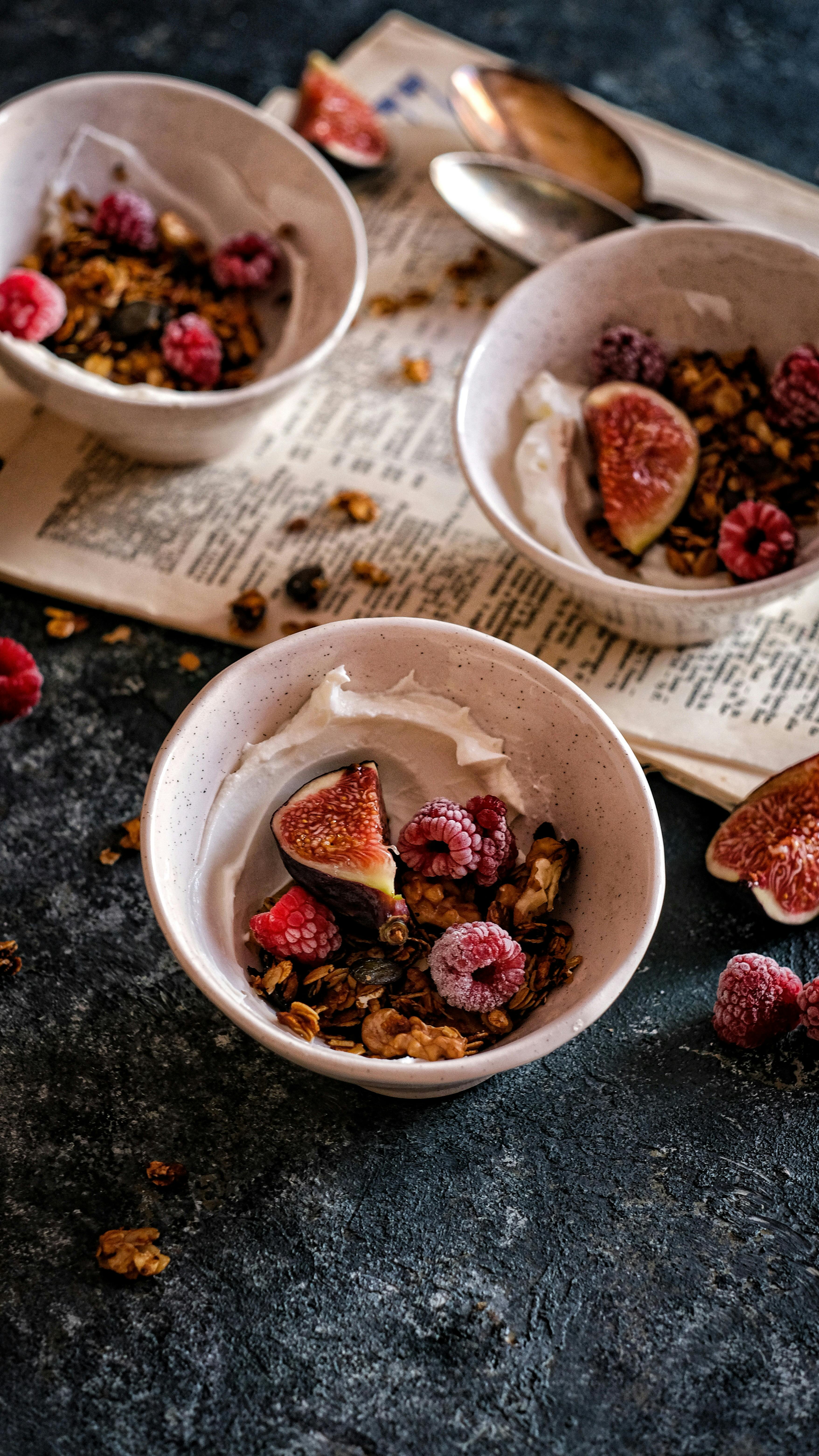 A healthy breakfast bowl with figs, raspberries, and granola on a vintage tabletop.