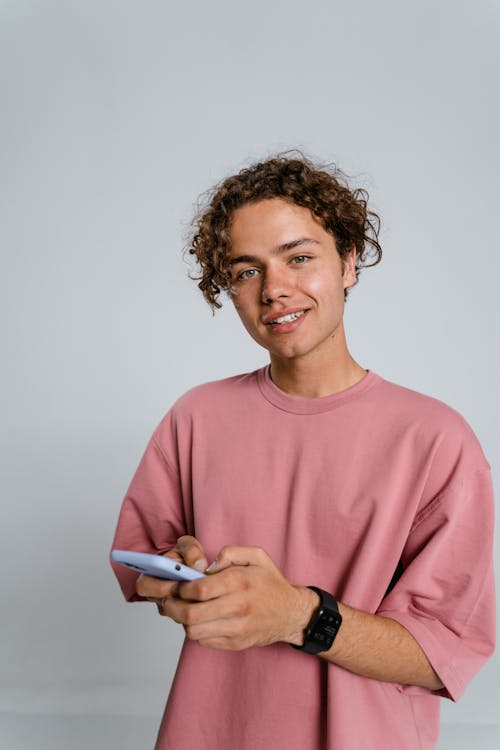 Man in Pink Crew Neck Long Sleeve Shirt Holding White Smartphone