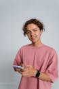 Man in Pink Crew Neck Long Sleeve Shirt Holding White Smartphone
