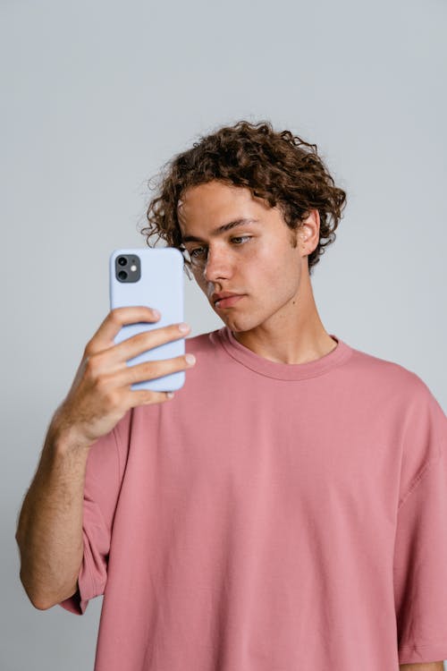 Man in Pink Crew Neck T-shirt Holding White Iphone 5 C