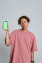 Man in Pink Crew Neck T-shirt Holding Blue and White Iphone Case