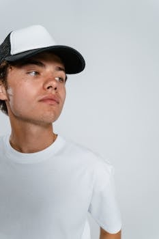 Casual portrait of a young man in a cap, looking away, studio shot.