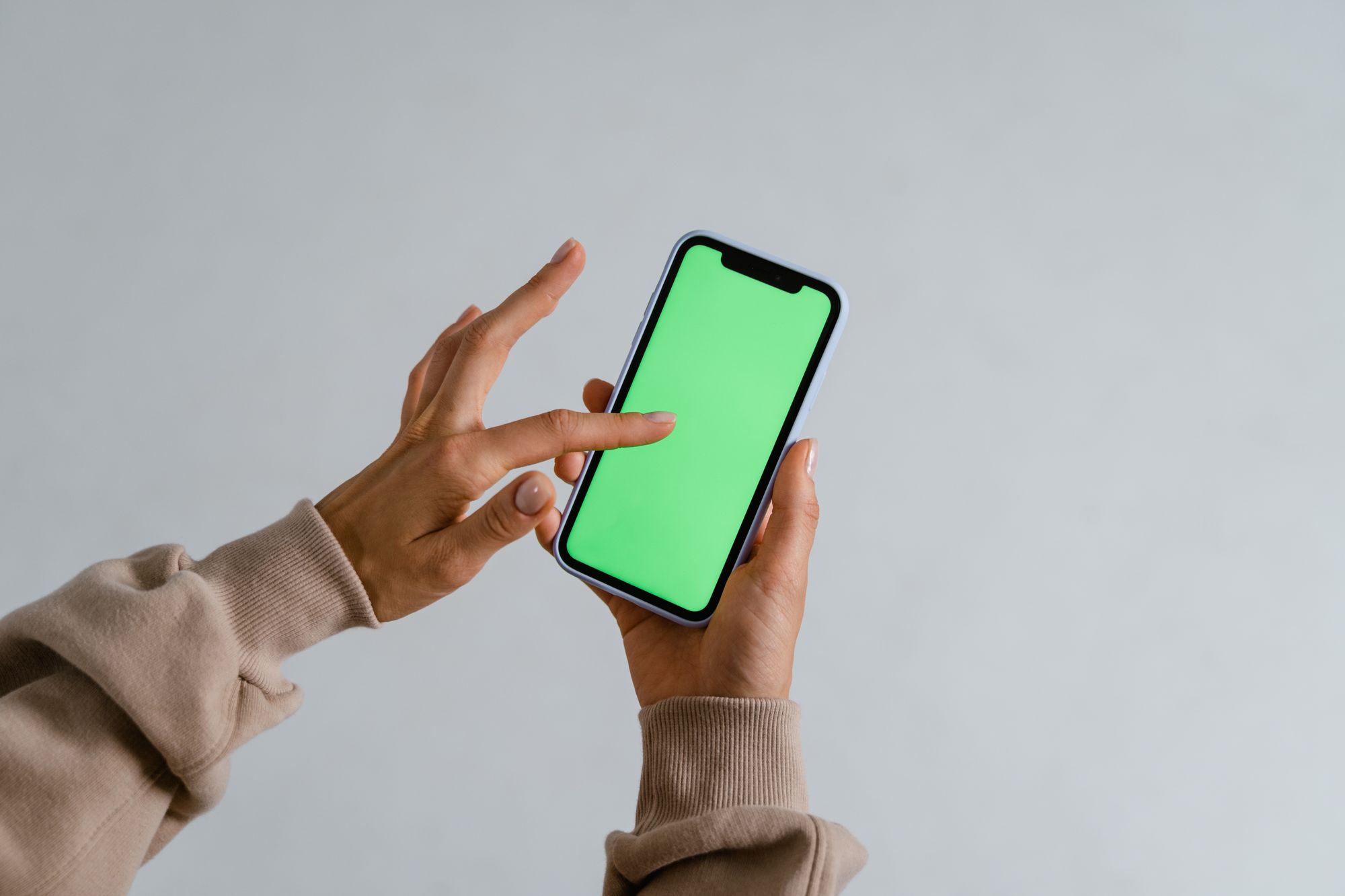 Manos sostienen un teléfono móvil mientras se desplaza un feed de videos verticales