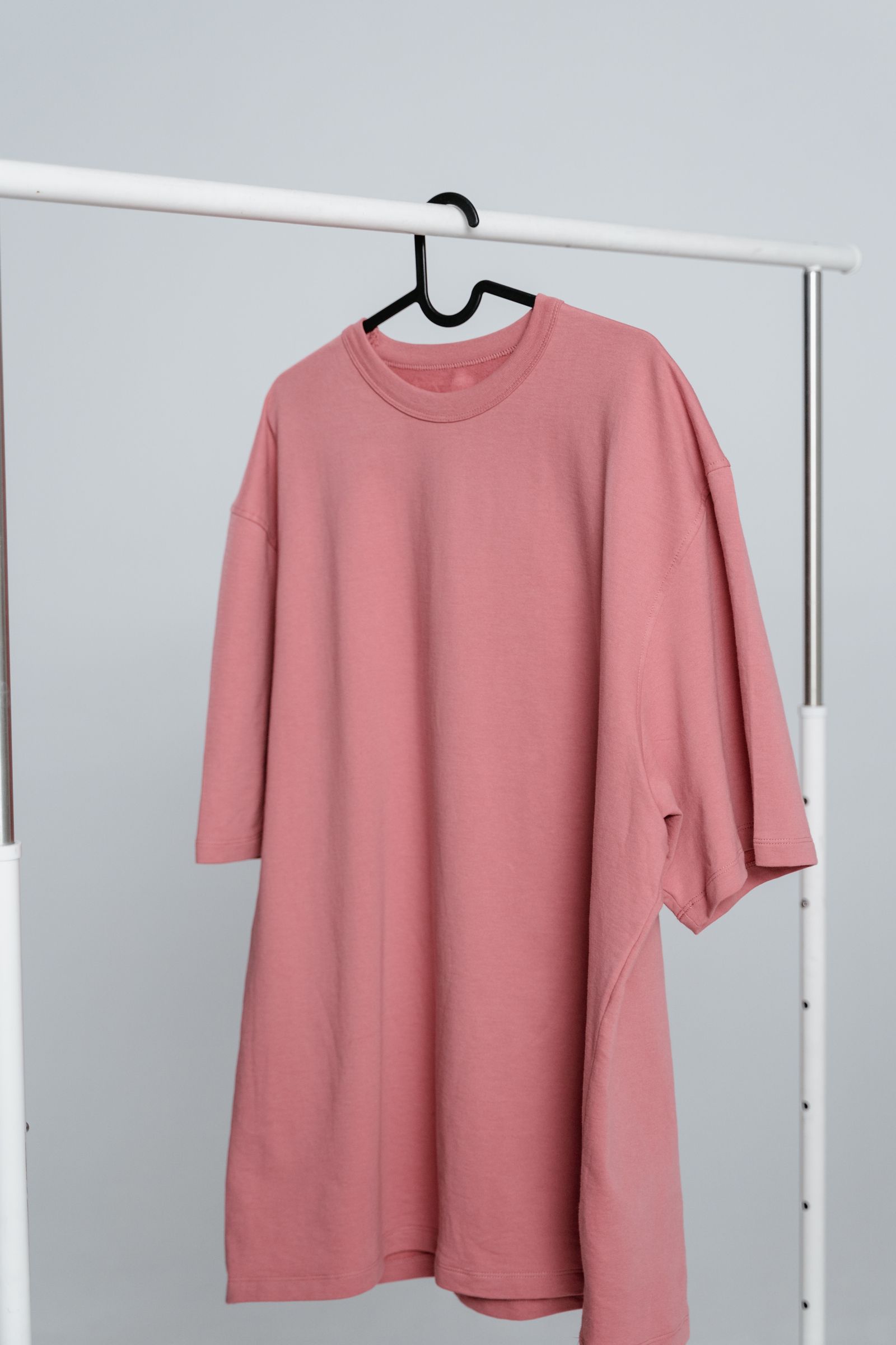 Simple pink crew neck T-shirt displayed on a hanger without people