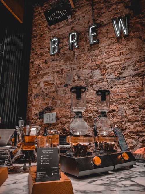 Free Warm and inviting coffee shop interior featuring a coffee dripper setup and vintage brick wall. Stock Photo