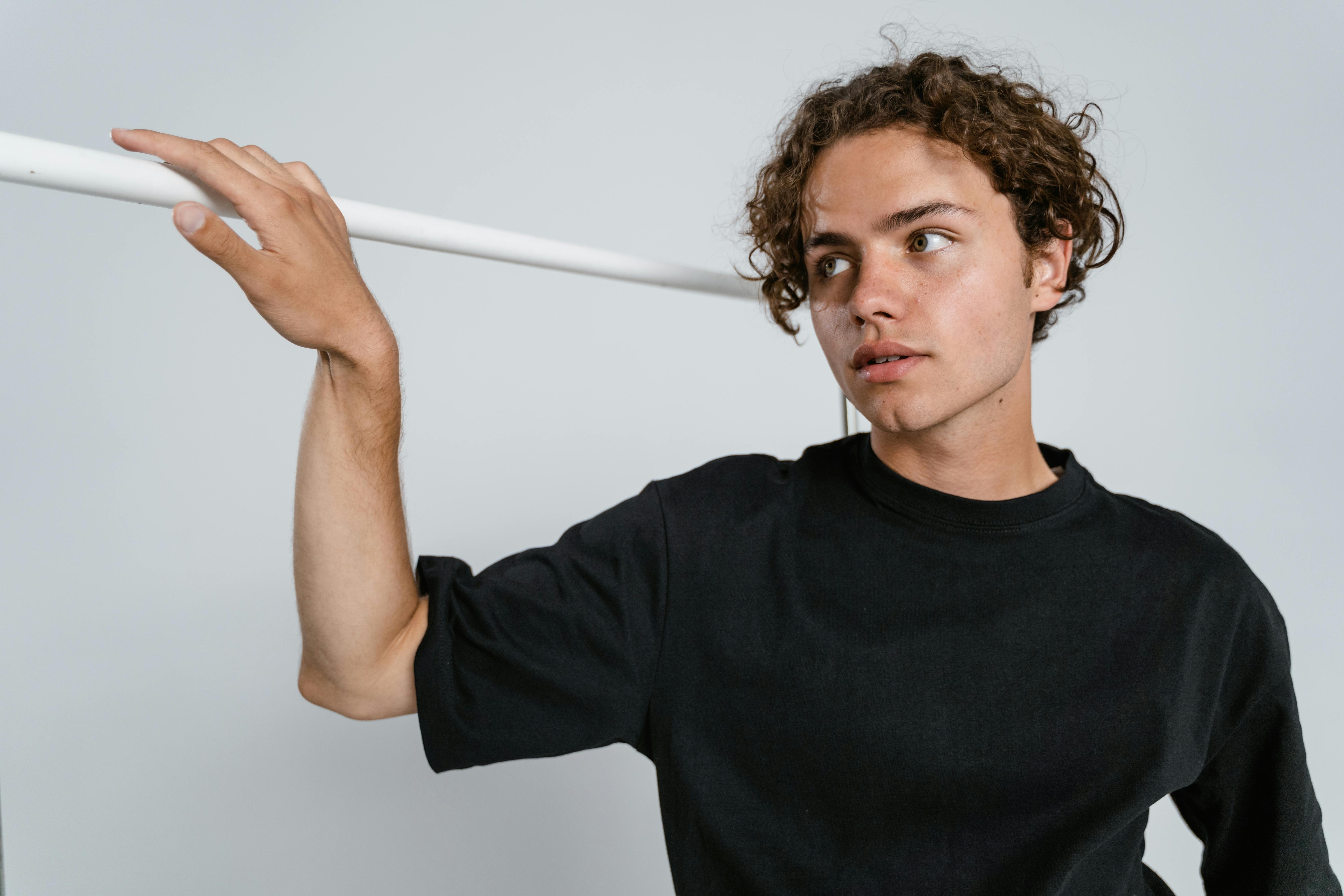 man in black crew neck t shirt holding white stick