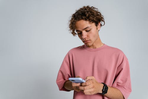 Man in Pink Crew Neck Sweater Holding White Smartphone