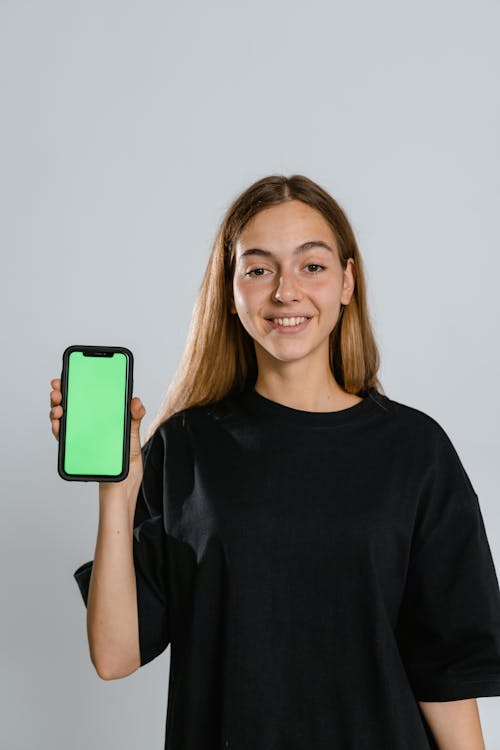Free Woman in Black Crew Neck T-shirt Holding Teal Iphone Case Stock Photo