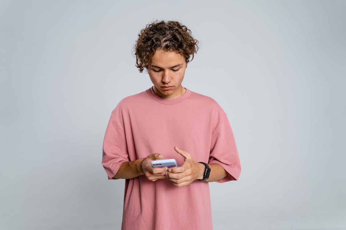 Free Woman in Pink Crew Neck Long Sleeve Shirt Holding Black Smartphone Stock Photo
